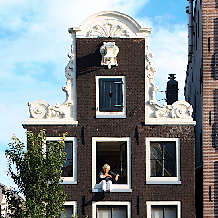 Lady sitting on window ledge of Canal house at Herengracht 35 Amsterdam with Neck Gable